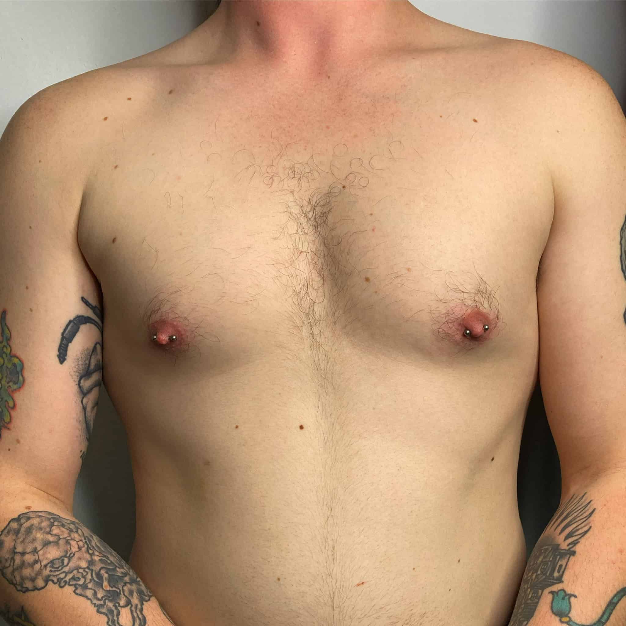 7sinstattoo.pl Osoba stoi na prostym tle, prezentując skomplikowane tatuaże na ramionach, bez koszulki. Z włosami na klatce piersiowej i widocznymi piercingami sutków, jej twarz pozostaje ukryta. Artystyczny szczegół odzwierciedla poziom umiejętności, jaki można znaleźć w najlepszym studio tatuażu w Poznaniu, przypominającym produkt 3F1C3B8C-CC41-4D4D-B656-91E896600EA7. Najlepsze studio tatuażu Seven Sins Tattoo