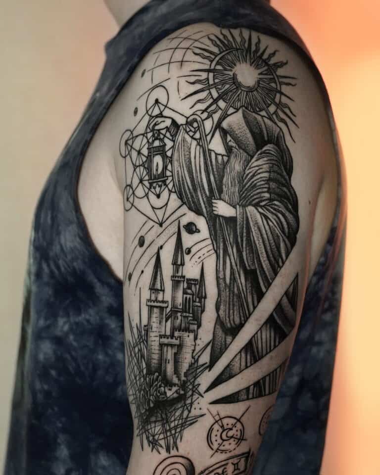 Na górnej części ramienia znajduje się szczegółowy czarno-szary tatuaż uchwycony jako DSC00054 przez 7sinstattoo.pl. Wzór przedstawia postać w szacie trzymającą latarnię, stojącą nad zamkiem z trzema wieżami. Skomplikowane tło obejmuje geometryczne kształty, słońce z promieniami i różne abstrakcyjne elementy. Osoba ma na sobie ciemną koszulę bez rękawów. Aby zobaczyć podobne arcydzieła, odwiedź nasze wiodące studio tatuażu w Poznaniu, Seven Sins Tattoo.