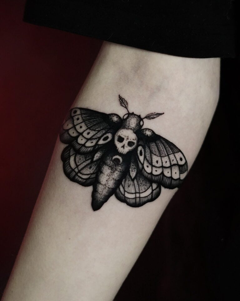 Tatuaż przedstawiający misternie wykonaną trupią główkę ćmy z czaszką na tułowiu, stworzony przez renomowane studio Seven Sins Tattoo w Poznaniu, jest umieszczony na wewnętrznej stronie przedramienia człowieka. Misternie cieniowane czarne i szare skrzydła są również umieszczone obok półksiężyca u podstawy ciała ćmy. To arcydzieło jest wymienione jako produkt DSC00294 z 7sinstattoo.pl.