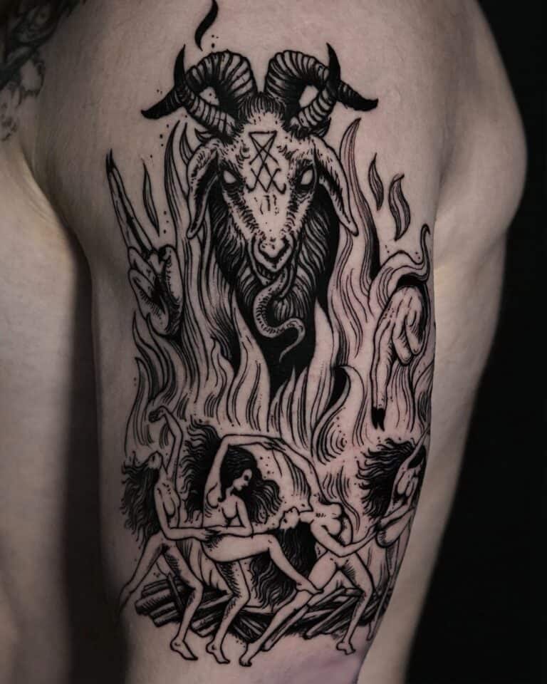 Szczegółowy czarny tatuaż na górnej części ramienia, stworzony przez artystę z najlepszego studia tatuażu w Poznaniu, Seven Sins Tattoo, przedstawia postać z głową kozy z rogami i okultystycznymi symbolami nad nią. Zatytułowany „DSC01117”, ten projekt przedstawia trzy nagie postacie w rozpaczy lub agonii, otoczone płomieniami i poskręcanymi gałęziami, prezentujące skomplikowane elementy ruchu i wysoki kontrast.