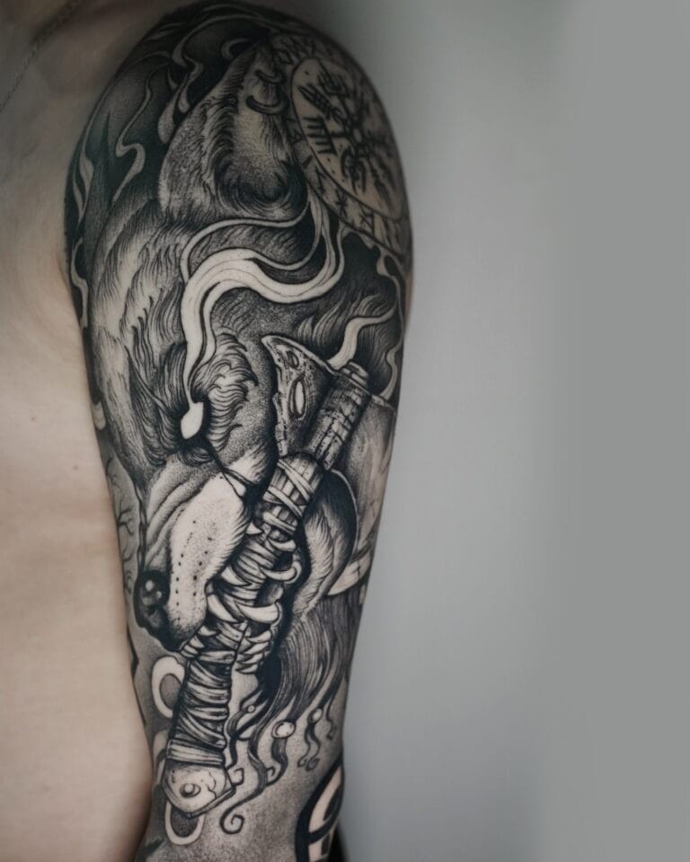 7sinstattoo.pl Czarno-szary tatuaż na ramieniu, uchwycony w produkcie DSC03452, przedstawia szczegółową głowę lwa z rozwianą grzywą, skomplikowany topór w stylu wikingów i skomplikowane wzory. Wzór rozciąga się od ramienia do połowy ramienia i jest mistrzowsko wykonany w najlepszym studio tatuażu w Poznaniu. Najlepsze studio tatuażu Seven Sins Tattoo