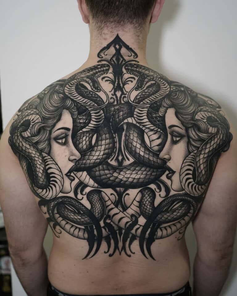 7sinstattoo.pl Osoba z misternym, czarno-szarym tatuażem pokrywającym całe plecy, znana jako DSC03455, przedstawia dwie kobiety zwrócone ku sobie, otoczone splecionymi wężami, tworząc symetryczny i wyszukany wzór. To arcydzieło zostało wykonane przez artystę ze studia tatuażu Poznań. Najlepsze studio tatuażu Seven Sins Tattoo