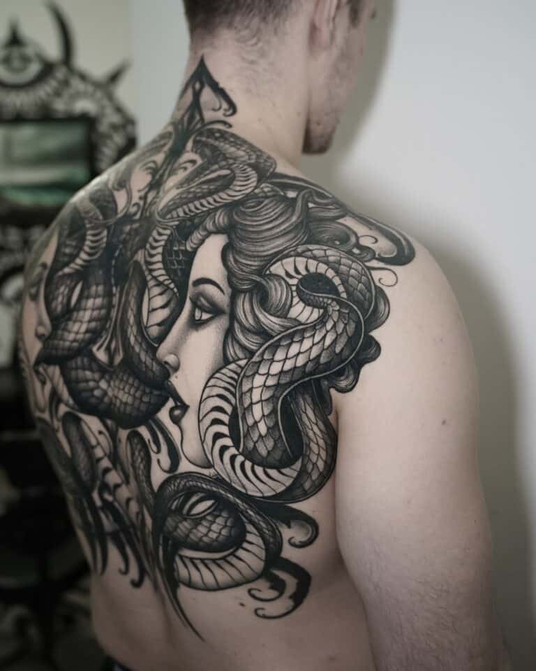 7sinstattoo.pl Osoba z dużym, szczegółowym tatuażem na plecach, przedstawiającym twarz kobiety przeplataną kilkoma realistycznie wyglądającymi wężami, wybrała DSC03480 ze względu na skomplikowane cieniowanie i faktury. Tatuaż rozciąga się od ramienia do ramienia i w dół do dolnej części pleców, prezentując kunszt najlepszego studia tatuażu Poznań. Najlepsze studio tatuażu Seven Sins Tattoo