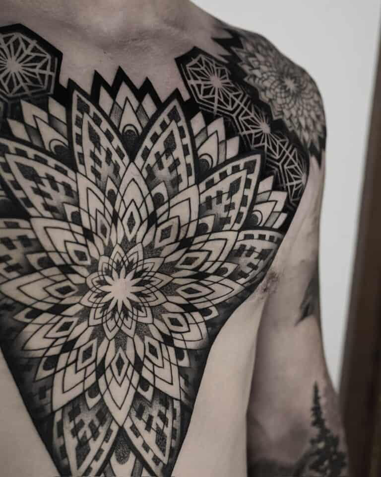 7sinstattoo.pl Zbliżenie górnej części klatki piersiowej i ramion osoby prezentuje rozległy i skomplikowany geometryczny wzór tatuażu z najlepszego studia tatuażu Poznań, zidentyfikowanego po nazwie produktu DSC04832. Tatuaż charakteryzuje się symetrycznymi wzorami i kształtami przypominającymi mandalę z czarnym i szarym cieniowaniem, pokrywającymi znaczną część skóry. Najlepsze studio tatuażu Seven Sins Tattoo
