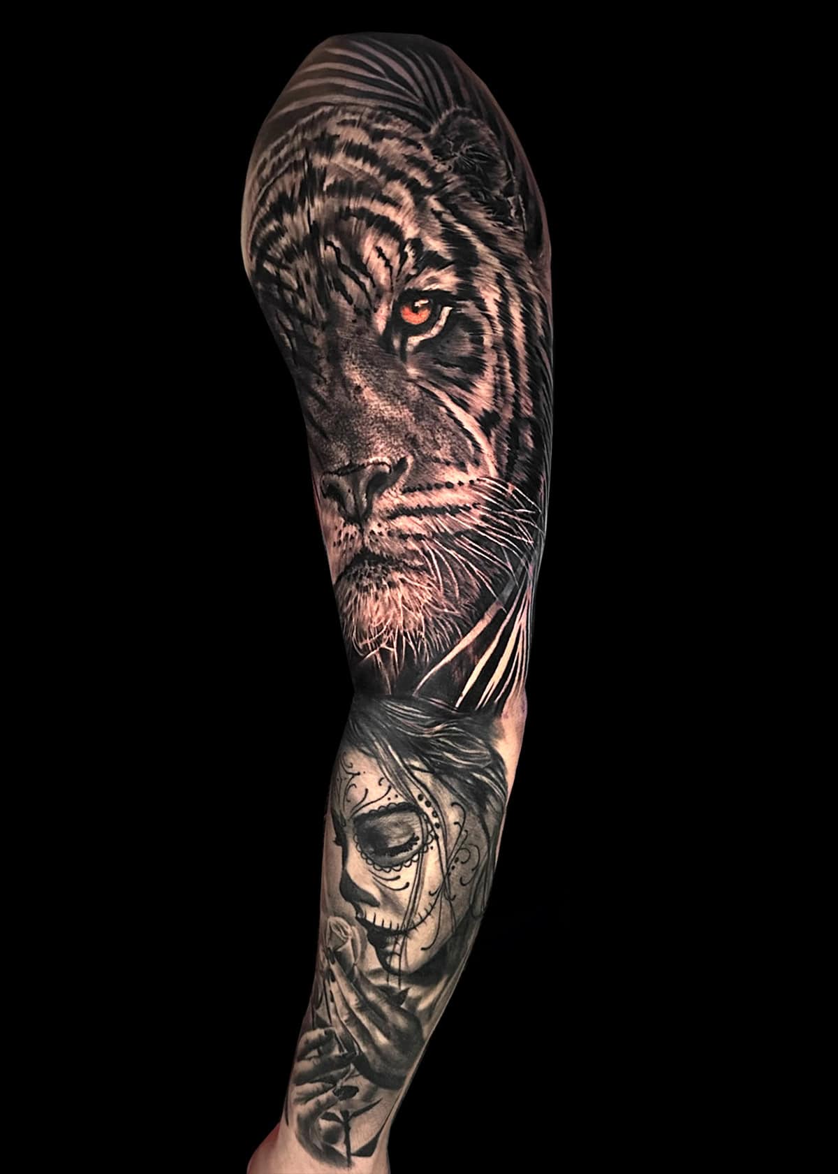 Pełny tatuaż na rękawie z realistyczną głową tygrysa u góry, przechodzący w szczegółowy, cieniowany portret kobiety ze skomplikowanymi oznaczeniami twarzy u dołu. Wzór jest monochromatyczny z cienkimi liniami i gładkim cieniowaniem, tworząc uderzający, spójny efekt wizualny.